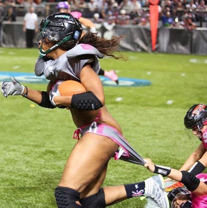 two women playing lacrosse on a field with people watching