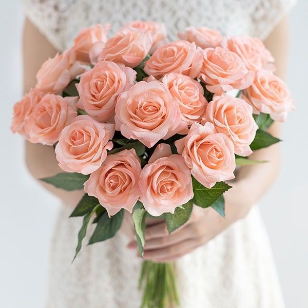 a woman holding a bouquet of pink roses