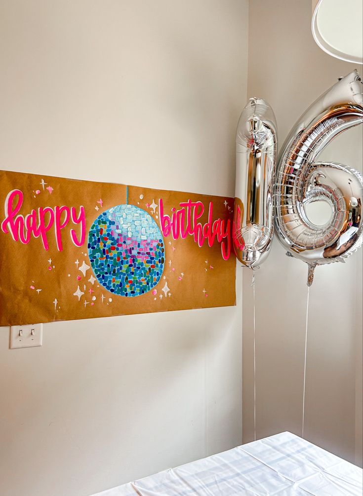 a birthday banner hanging on the wall next to a bed with balloons and streamers