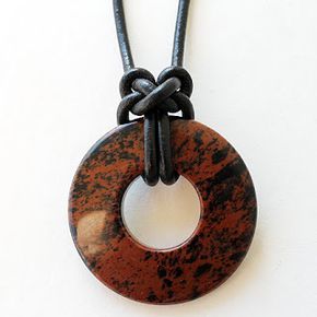 a brown and black necklace with a circular pendant hanging from it's end on a leather cord