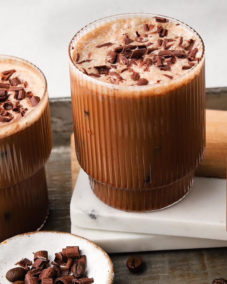 two glasses filled with chocolate and topped with nuts