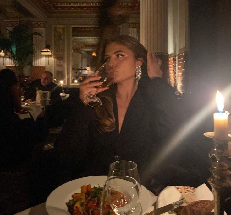 a woman sitting at a table drinking wine