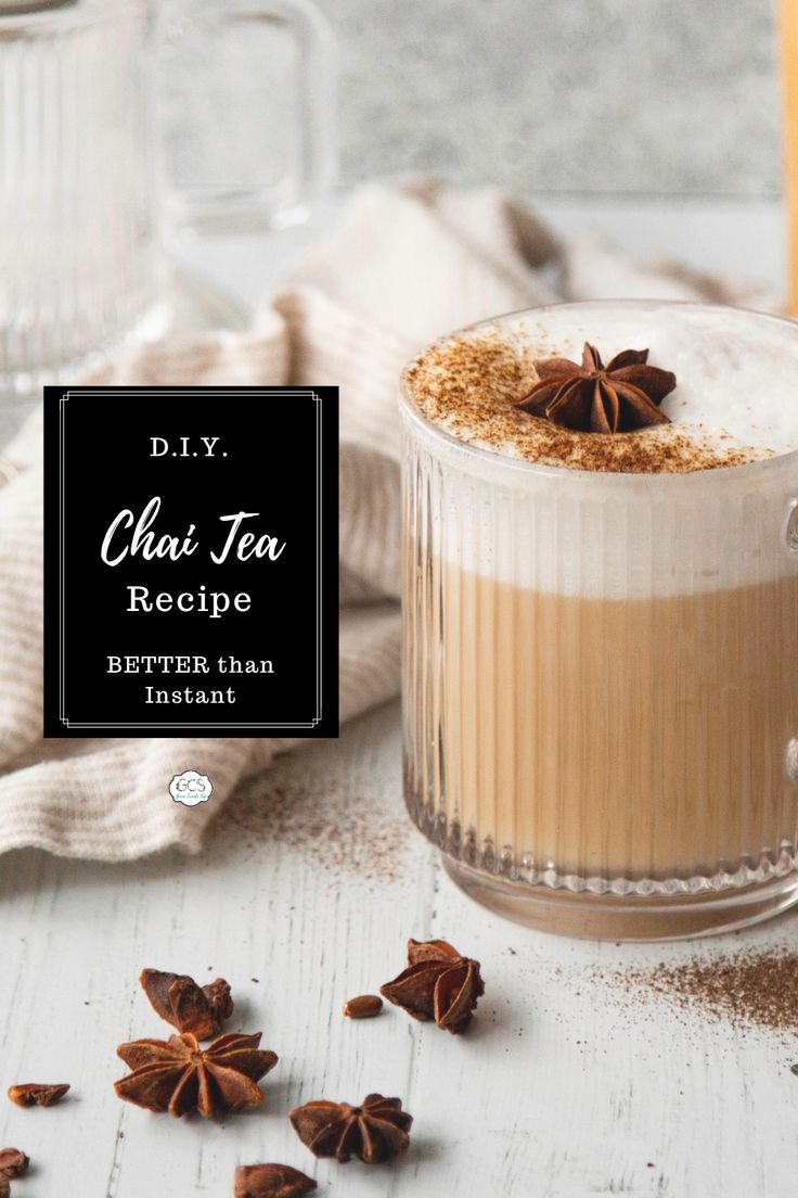 a glass mug filled with chai tea on top of a white table next to cinnamons