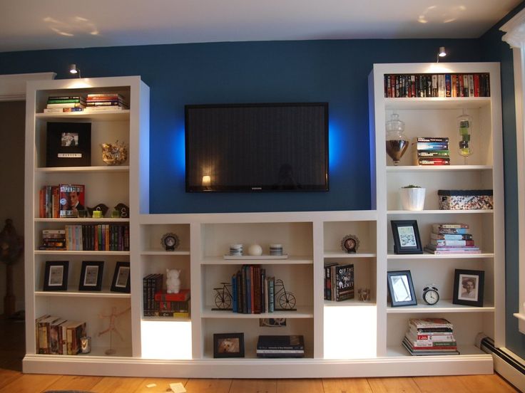 a living room with bookshelves and a flat screen tv mounted on the wall