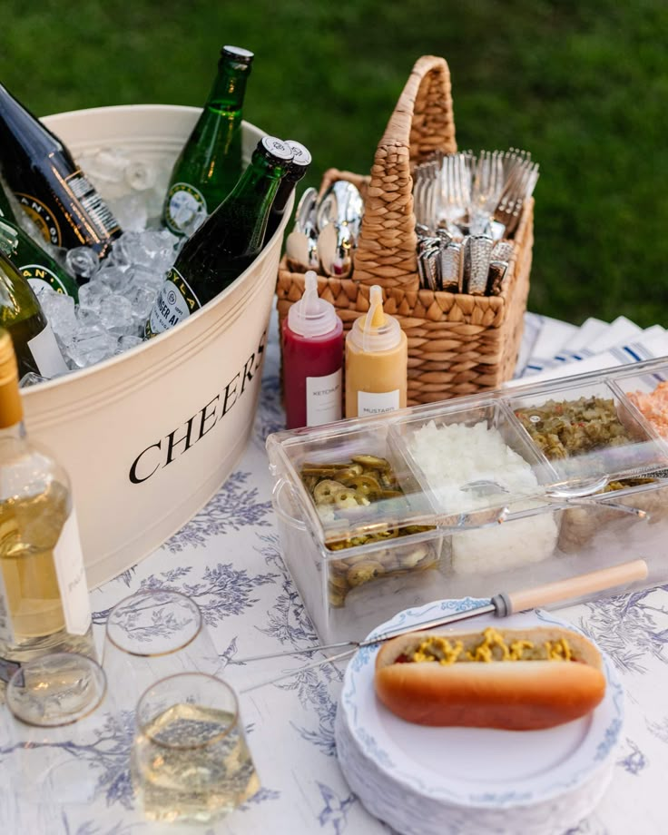 a hot dog sitting on top of a table next to bottles of wine and condiments