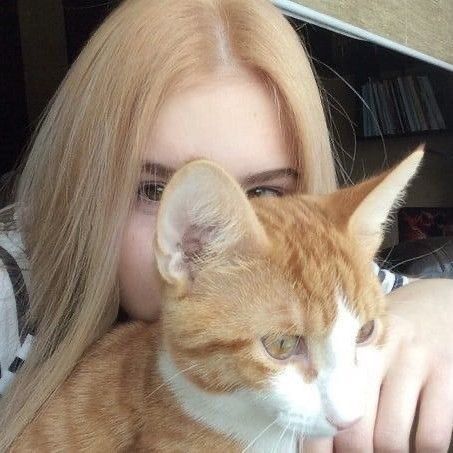 a woman with long blonde hair holding a cat