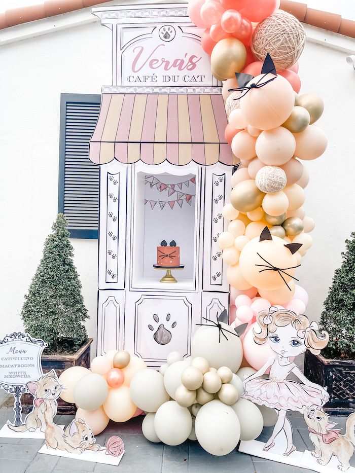 an assortment of balloons on display in front of a storefront with dogs and cats