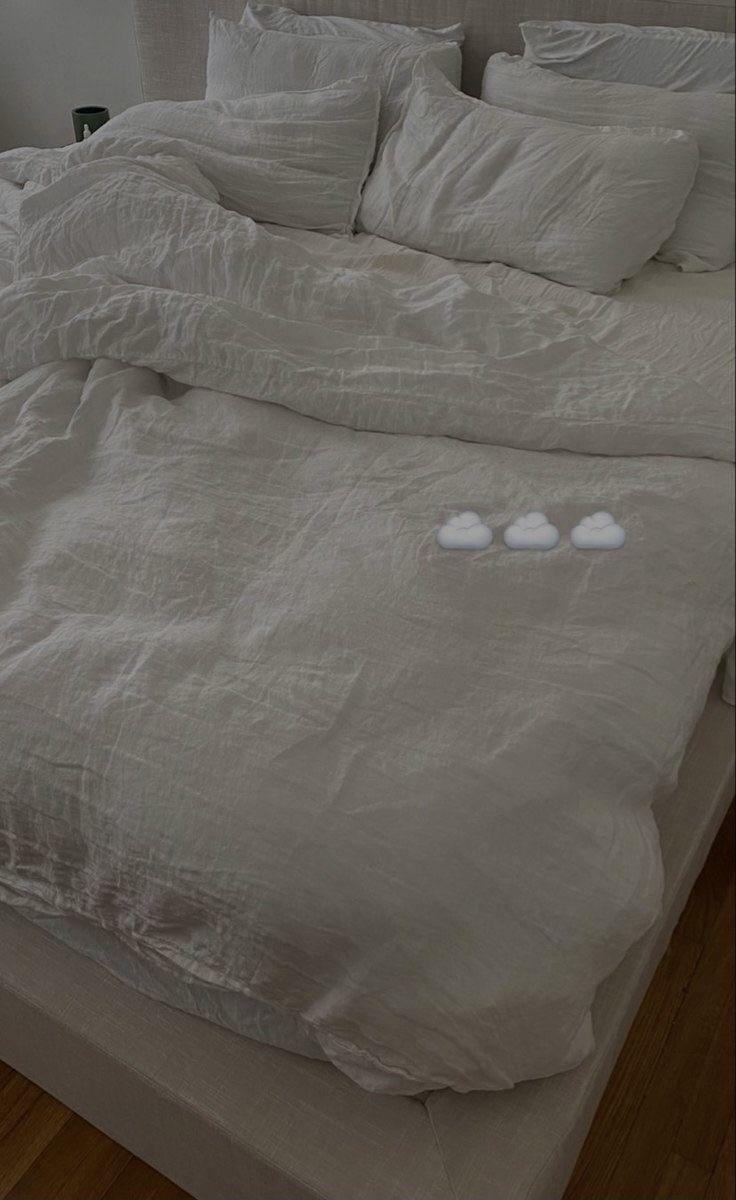 an unmade bed with white sheets and pillows