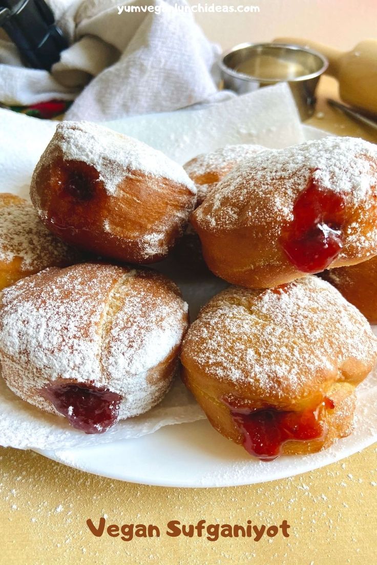 some powdered doughnuts are on a plate with jam and powdered sugar