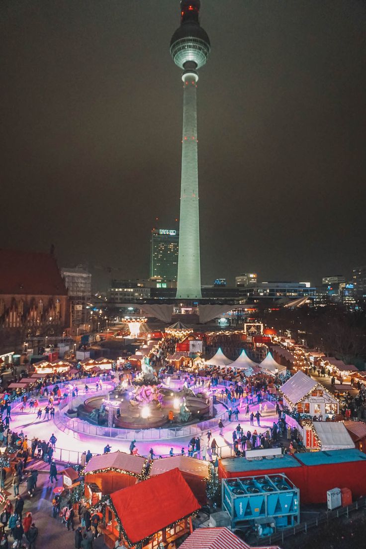 an aerial view of the christmas market in front of the television tower at night time