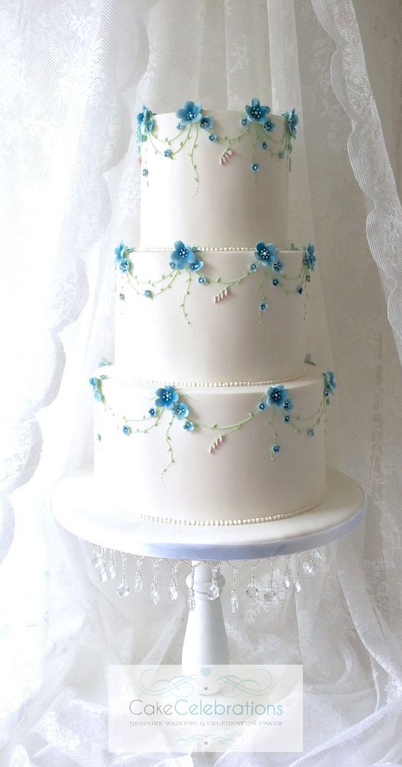 a three tiered white cake with blue flowers on it