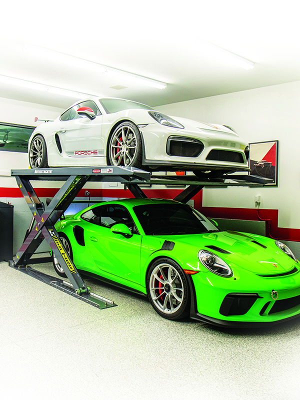 two cars are parked on top of each other in a garage with one being lifted by a scissor