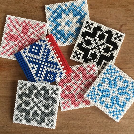 four cross stitch coasters on a wooden table