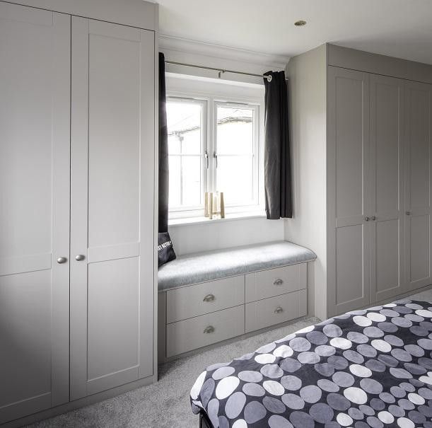 a bedroom with gray and white furniture and a black and white polka dot bedspread