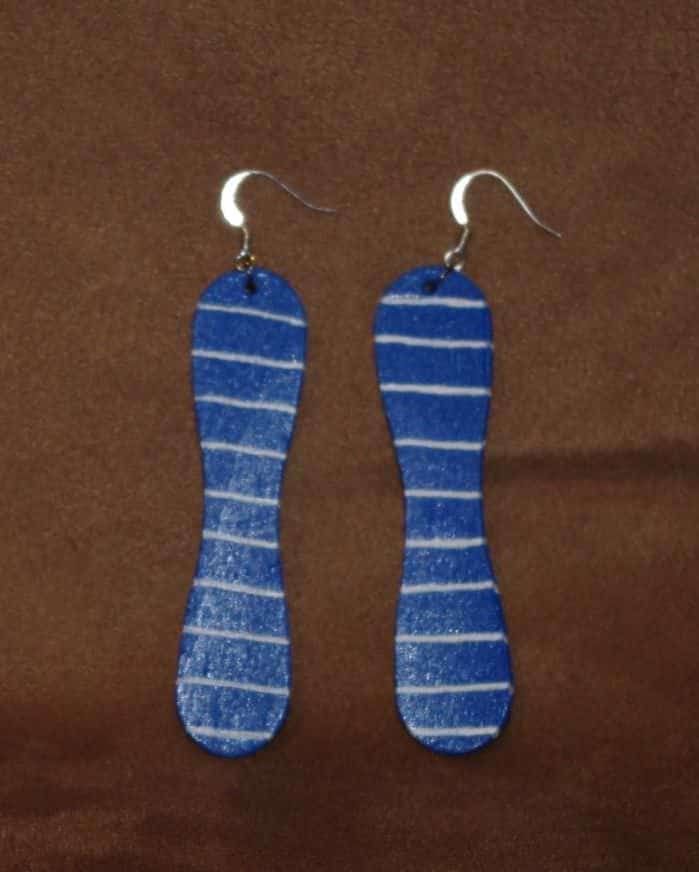 pair of blue and white striped earrings on brown fabric with silver earwires hanging from hooks