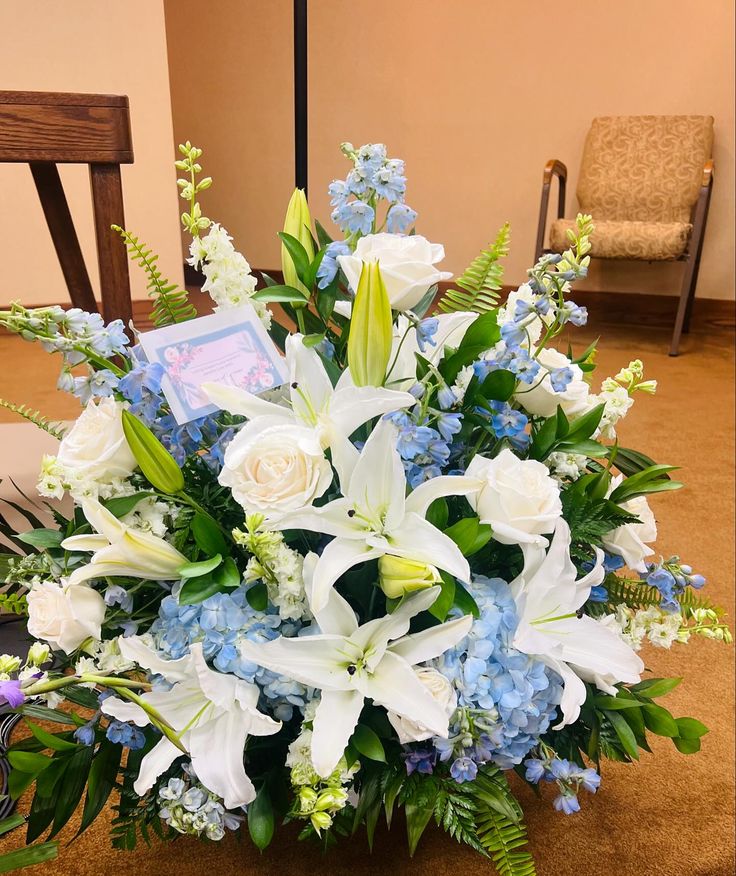 a bouquet of white and blue flowers sitting on the floor in front of a chair