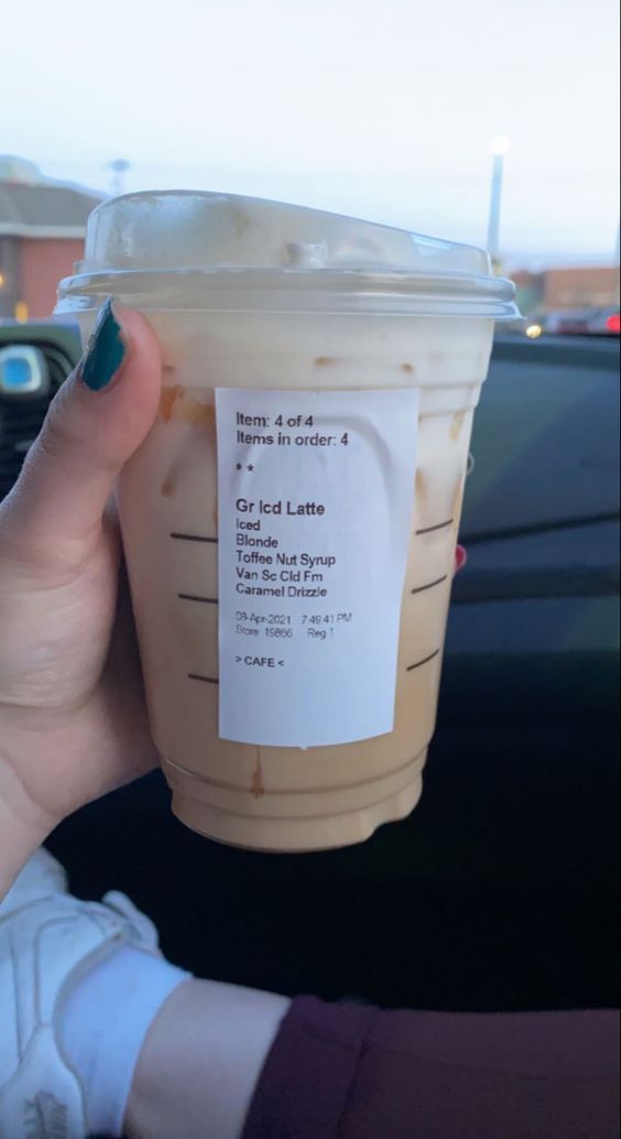 a woman holding up a cup of iced coffee in her hand with the label on it