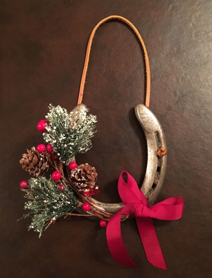 a christmas decoration made out of horseshoes and pine cones with a red ribbon tied around it