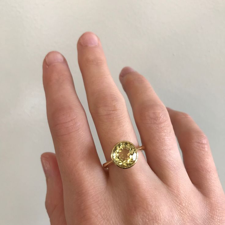 a woman's hand with a yellow diamond ring on top of her left hand