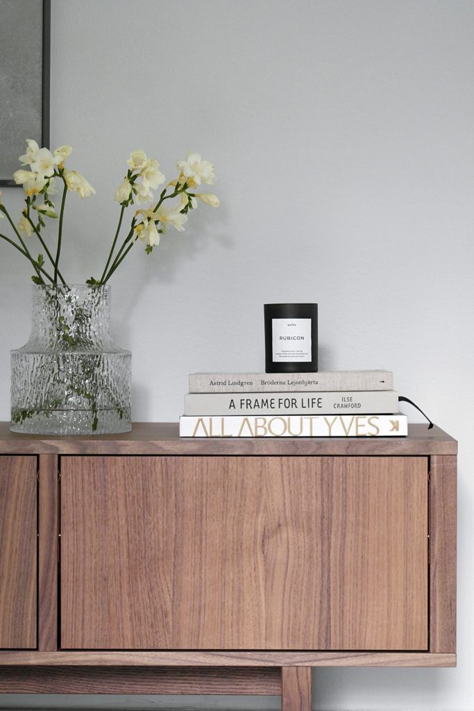 a wooden cabinet with flowers and books on top