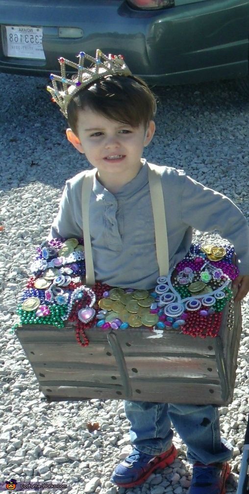 a little boy that is standing in the dirt with a basket full of beads on his head