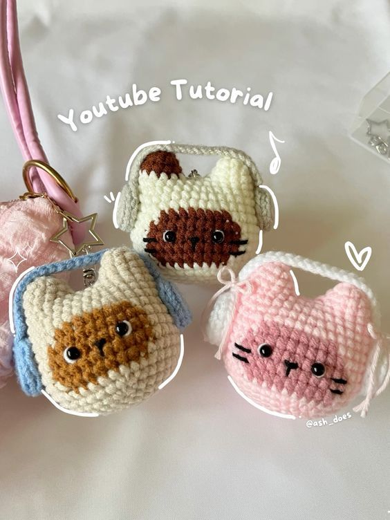 three small crocheted purses with cats on them, one is pink and the other is blue