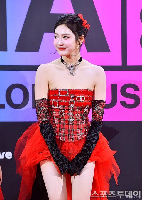 a woman in a red and black dress is posing for the camera with her hands on her hips