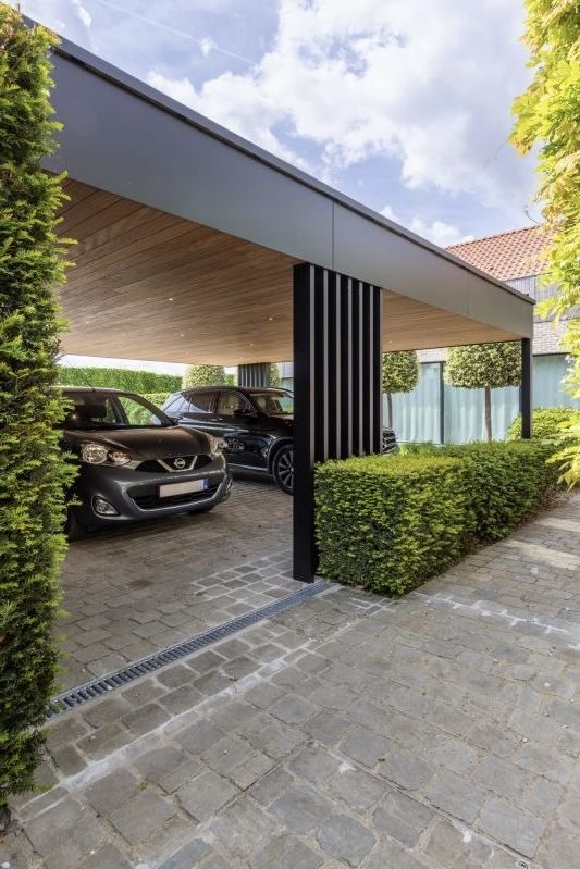 two cars are parked in the driveway under an awning