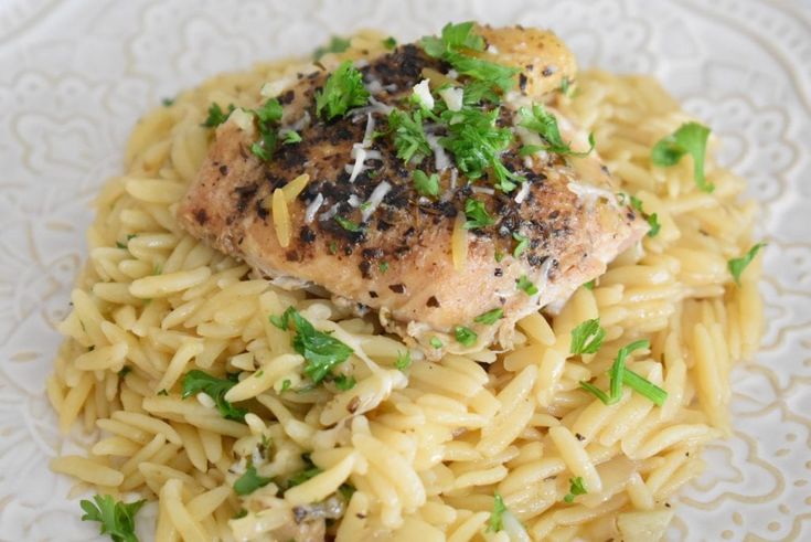 a white plate topped with pasta and meat covered in parmesan sprinkles