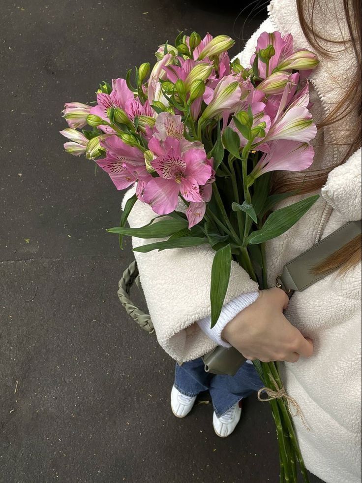 a woman holding a bouquet of pink flowers