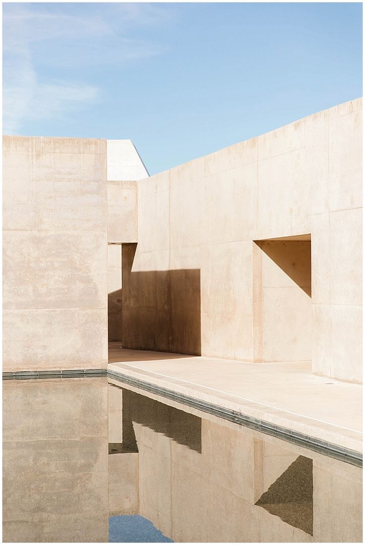 an empty pool in front of a building with no people on the ground and one person standing