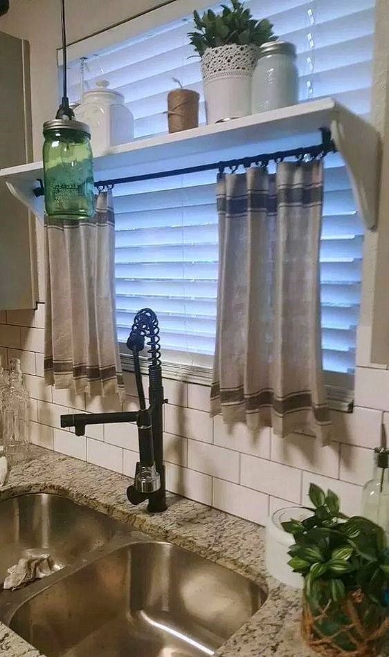 a kitchen sink with a faucet next to a window covered in curtains and potted plants