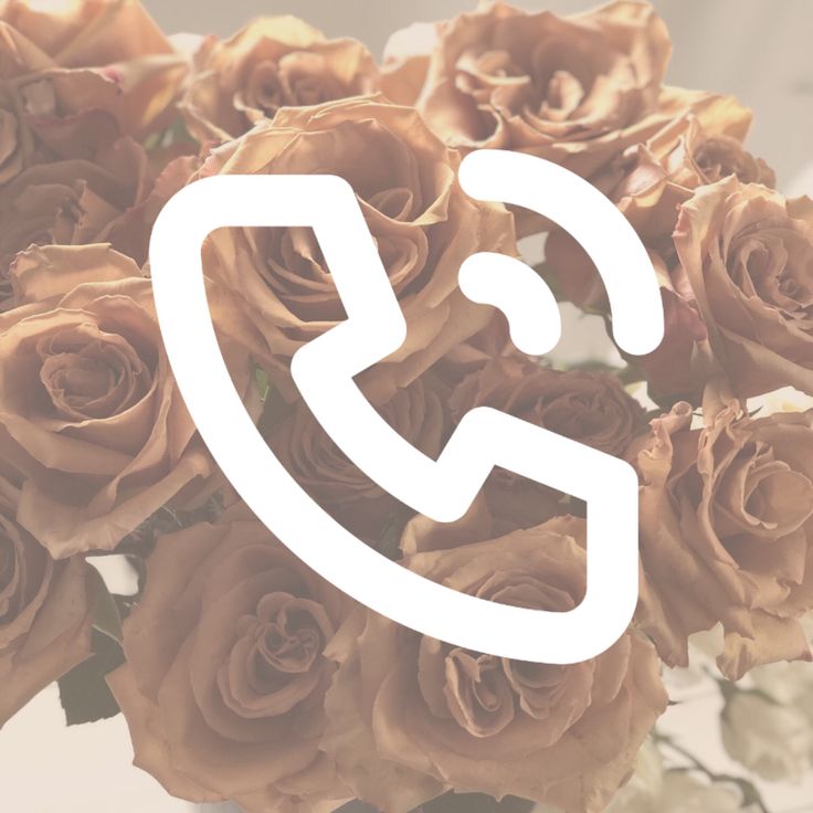 a vase filled with lots of brown roses next to a phone call sign on top of it