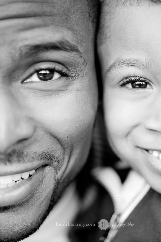 a black and white photo of a smiling man with his arm around a child's head