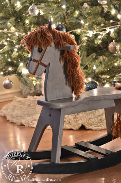 a wooden rocking horse sitting in front of a christmas tree