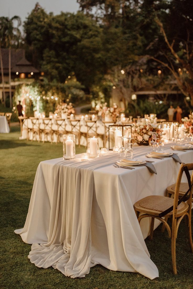 an outdoor dinner table with candles and plates