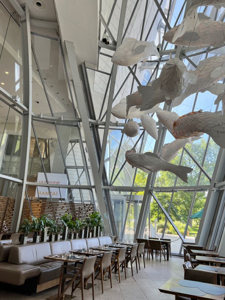 the inside of a restaurant with many tables and chairs in front of large glass windows