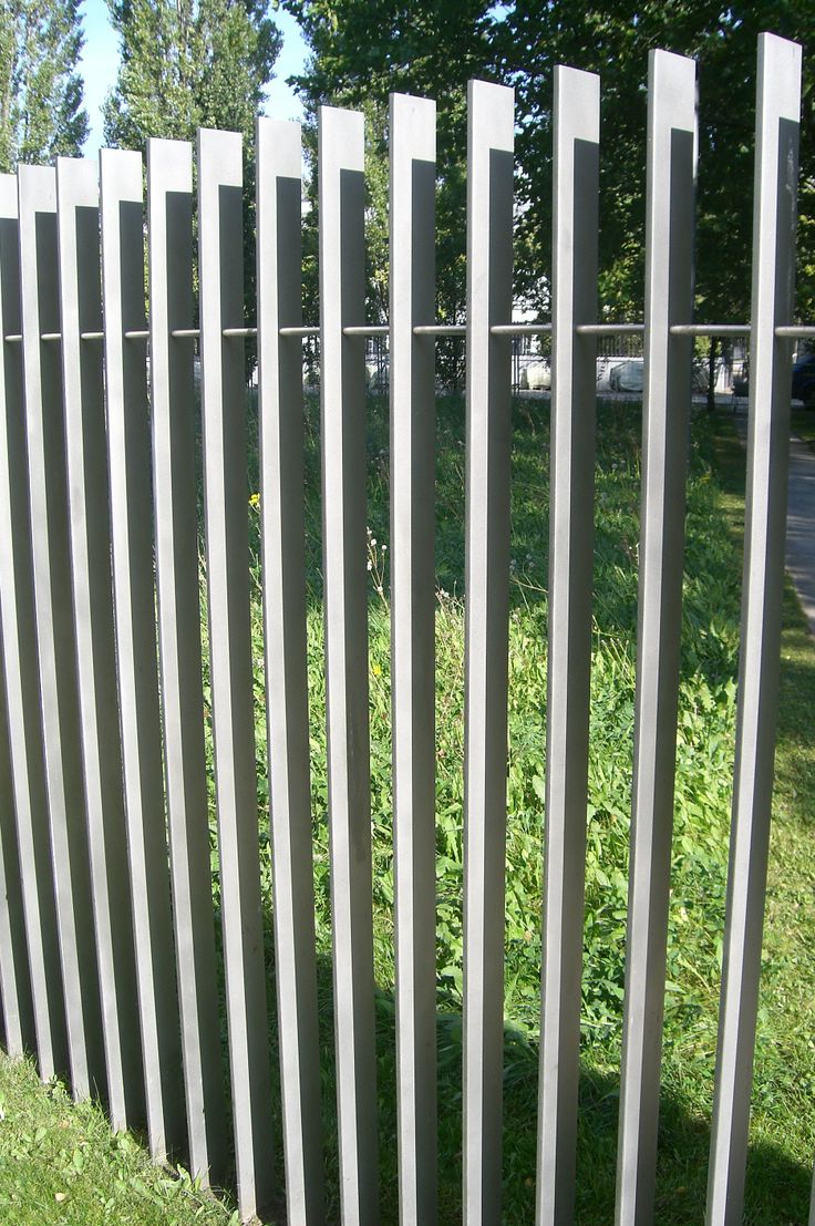 a close up of a fence with grass and trees in the background