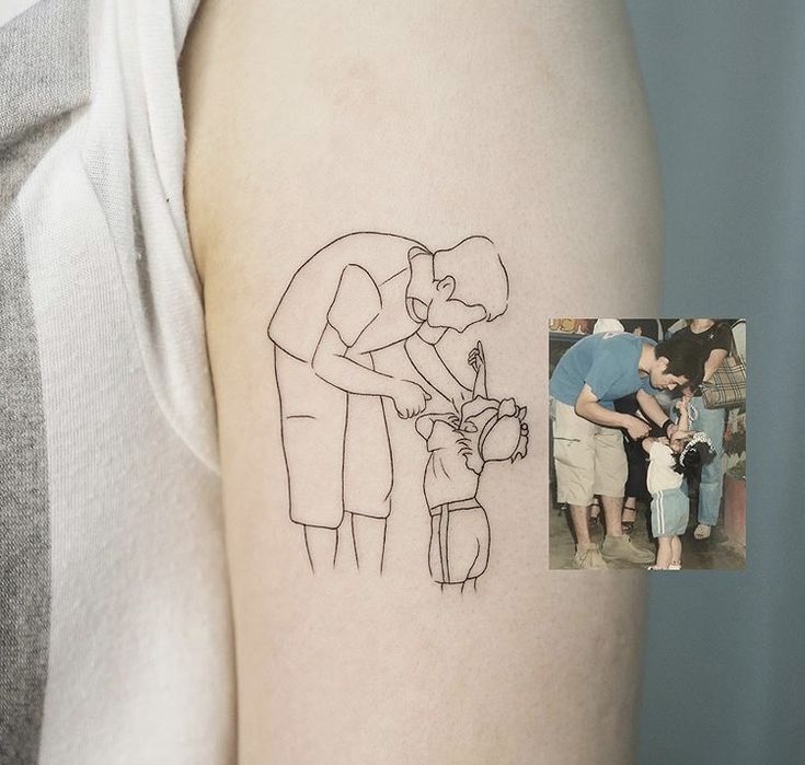 a person with a small tattoo on their arm is holding a child's hand