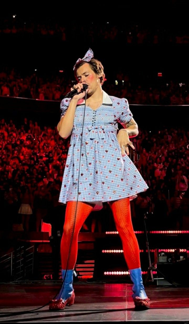 a woman standing on top of a stage holding a microphone in her hand and wearing red tights