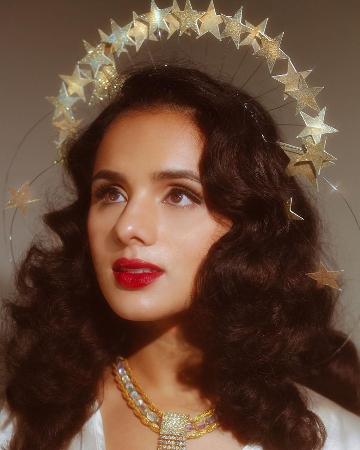 a woman wearing a tiara with gold stars on it's head and red lipstick