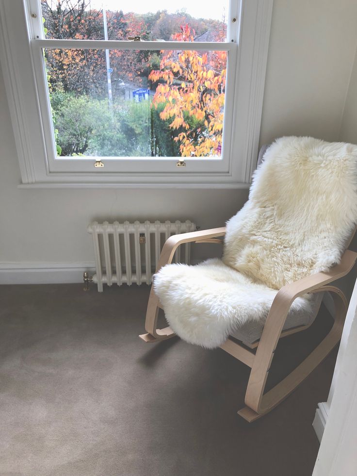 a white rocking chair sitting in front of a window next to a radiator