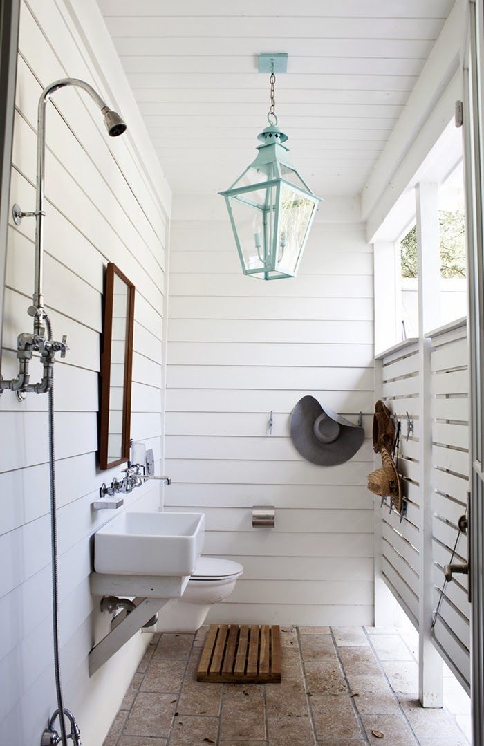 a bathroom with white walls and wood flooring next to a light hanging from the ceiling