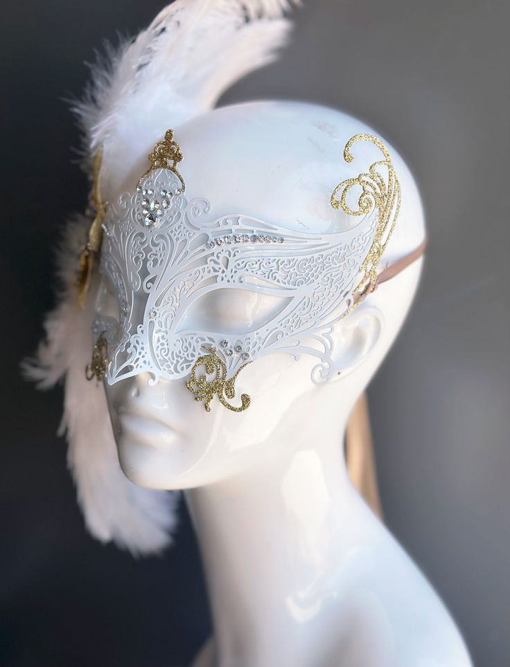 Our women's white laser cut metal masquerade mask, adorned with delicate white feathers and a gold crystal brooch, offers you the opportunity to add a touch of enchanting gold glitter to the mask. Whether you're attending a grand masquerade ball, a themed gala, or simply looking to add a touch of elegance to your attire, this mask ensures you'll be the center of attention. Age Group/Gender - Adult/Women Size/Type - One size fits all adults Mask Color - White Mask Material - Laser cut metal Gold And White Masquerade Mask, Female Masquerade Mask, Angel Mask Masquerade Ball, Dove Mask Masquerade, Masquerade Mask Feathers, Masquerade Dress And Mask, Masquerade Masks Diy, Juliet Core, Fantasy Masks