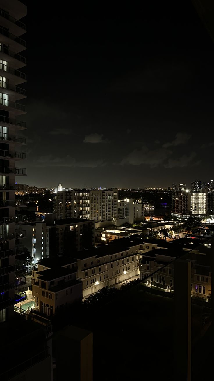 the city is lit up at night with buildings in the foreground and skyscrapers in the background