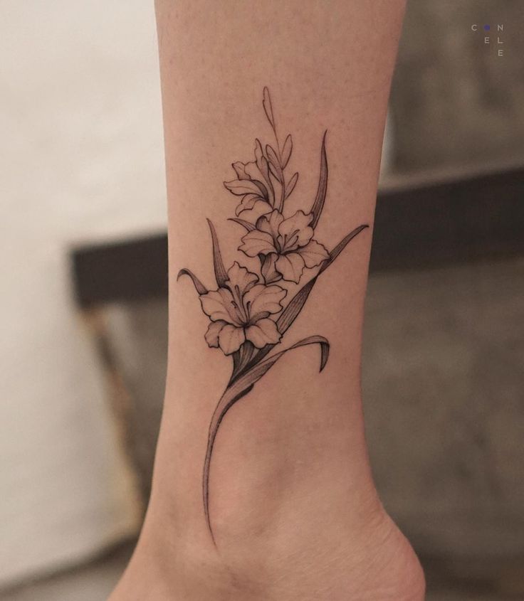 a flower tattoo on the ankle is shown in black and grey ink, with white flowers