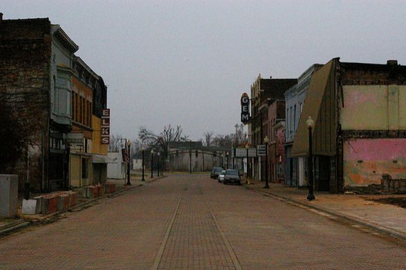 an empty street with buildings and cars parked on the side