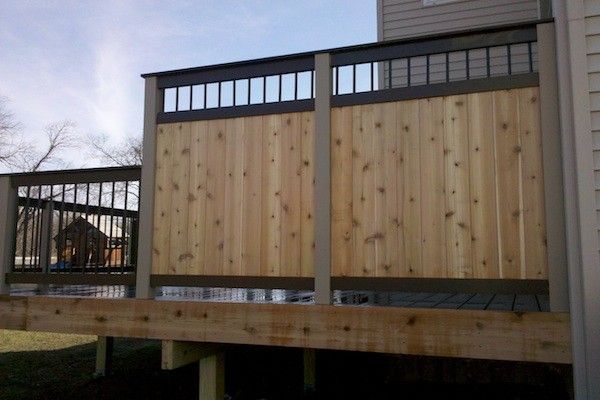 a wooden deck next to a house with metal railings