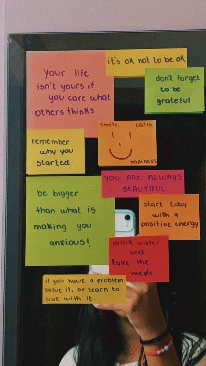 a woman taking a selfie with sticky notes attached to her face and hand written on the wall