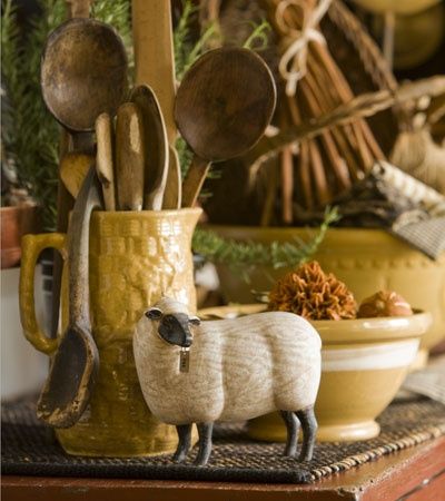 a sheep figurine sitting on top of a table next to utensils